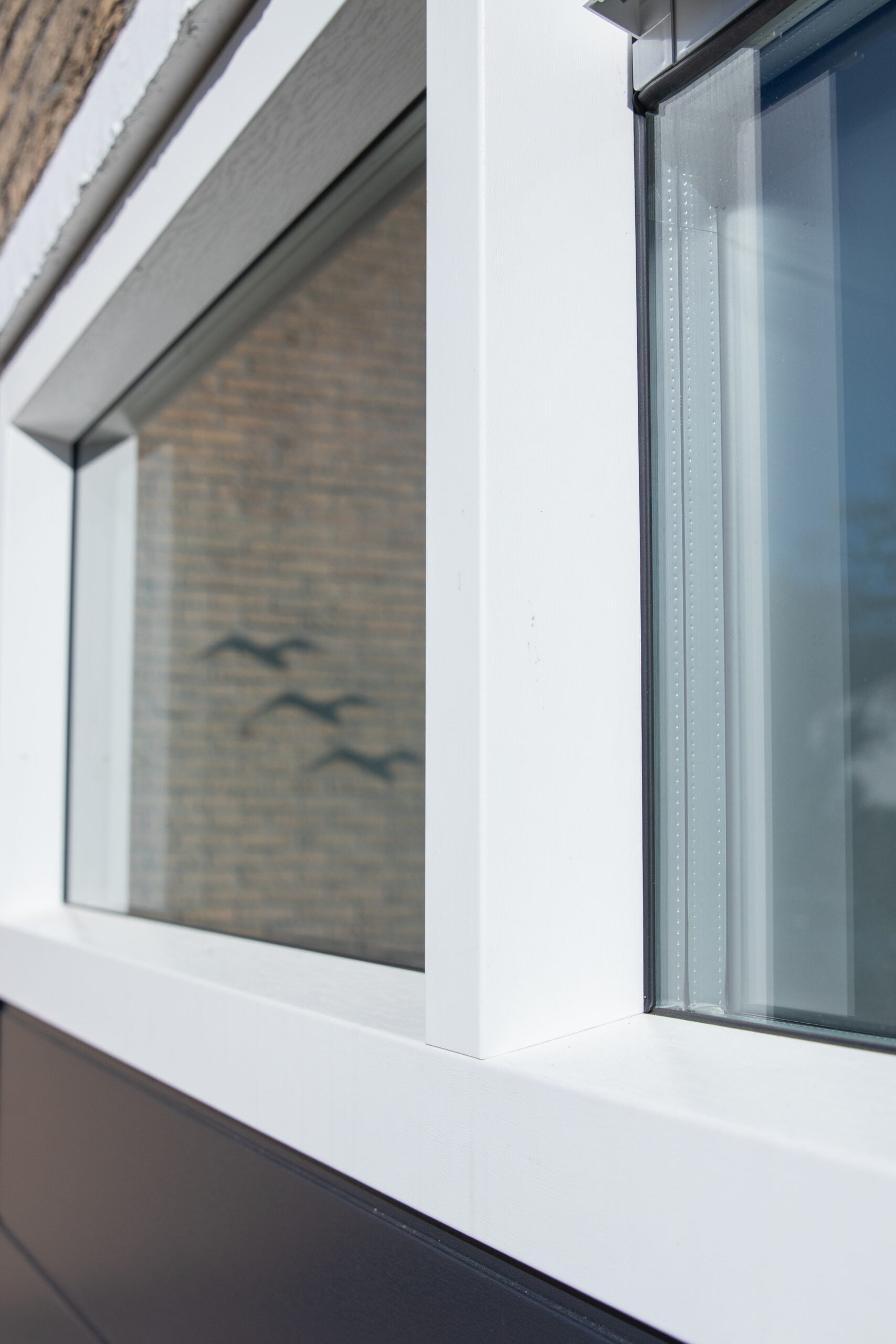 Detail van een wit kunststof kozijn met strakke afwerking tegen metselwerk.